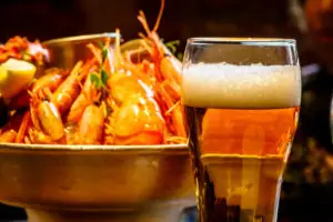 A glass of beer in the background is a plate of crab, shrimp, sc