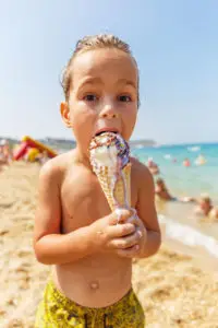 Beautiful boy is eating an ice cream on the beach